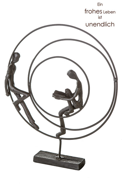 Die Skulptur "Circles" rundes Kunstobjekt aus brüniertem Eisen bestehend aus drei einzelnen Kreisen. Im äußeren und inneren Kreis sitzt je eine Figur. Die Figur im inneren Kreis liest ein Buch.