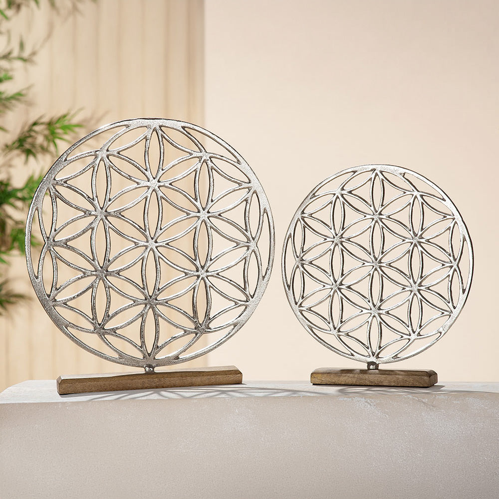 Die Skulptur in runder Form des Mandalas Lebensblume aus Aluminium steht auf einer Holzbasis aus braunem Mangoholz.