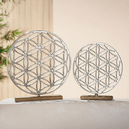 Die Skulptur in runder Form des Mandalas Lebensblume aus Aluminium steht auf einer Holzbasis aus braunem Mangoholz.