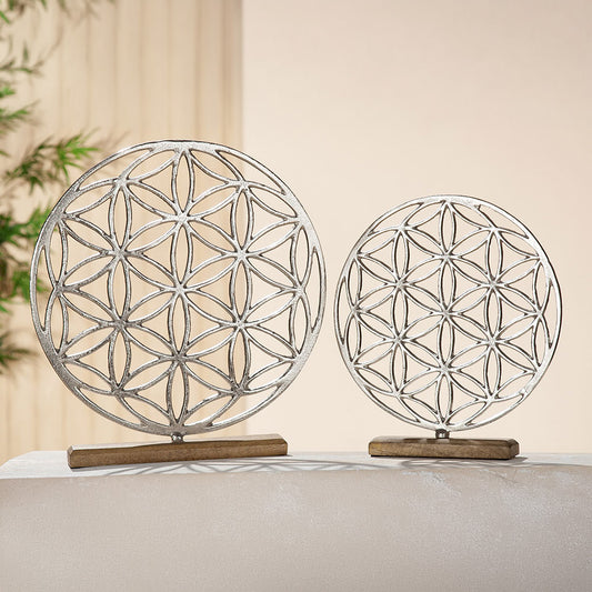 Die Skulptur in runder Form des Mandalas Lebensblume aus Aluminium steht auf einer Holzbasis aus braunem Mangoholz.