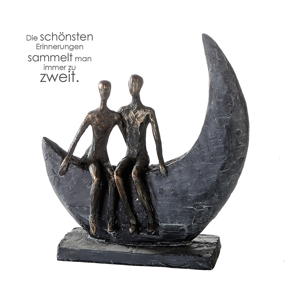 Die bronzefarbene Design Skulptur „Moon“ stellt ein auf einem liegenden Halbmond nebeneinandersitzendes Paar dar.