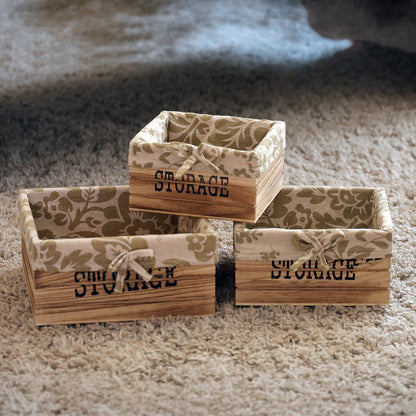 aufbewahrungskörbe aus braunem holz mit der aufschrift storage und mit beige gemusterter leinenstoffeinlage. 3er set in drei unterschiedlichen größen, rechteckig ohne deckel