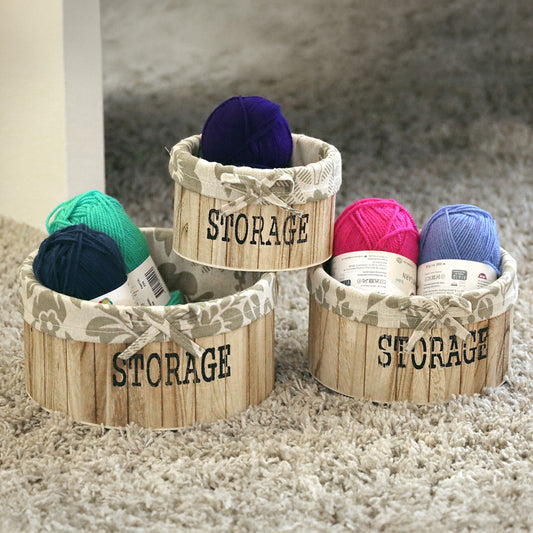 aufbewahrungskörbe aus hellbraunem holz mit der aufschrift storage und mit beige gemusterter leinenstoffeinlage. 3er set in drei unterschiedlichen größen, rund ohne deckel