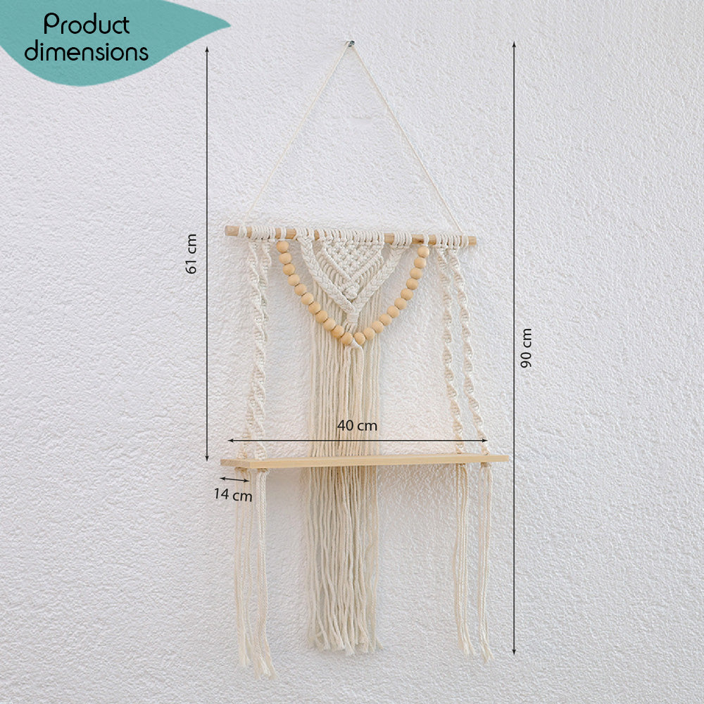 DECCARO Makramee-Hängeregal Bead. Vertikale Holzstange an der Baumwollseile befestigt sind, die mit einem stabilen, schmalen Holzbrett verknüpft sind. Weiterhin ist an der Holzstange ein Makramee Knotenmuster mit vielen kleinen Holzperlen befestigt, die die Optik des Regals abrunden.