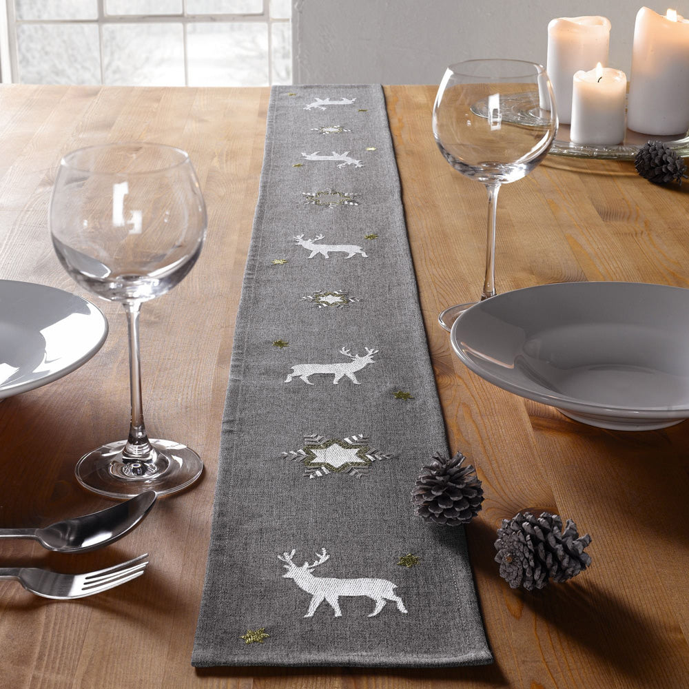 Tischband Winter aus einem matten Grundstoff in Dunkelgrau mit aufwändig bestickten Eiskristallen, Sternen und Hirschen. Die Stickereien schimmern in Silber und Gold.