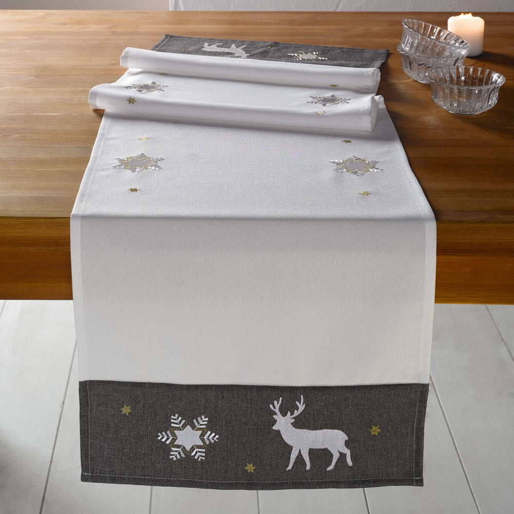 Tischläufer "Winter" aus einem matten Grundstoff in elegantem Champagner mit einer breiten, dunkelgrauen Borde, Tischläufer aufwändig mit Eiskristallen, Sternen und Hirschen bestickt. Die Stickereien schimmern in Silber und Gold.