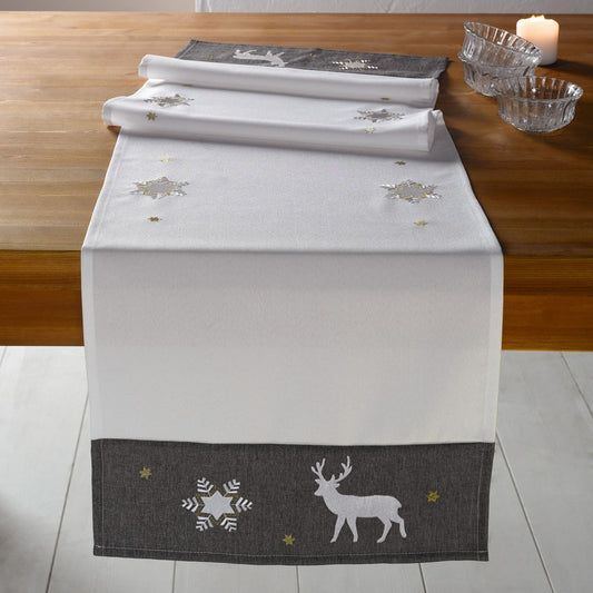 Tischläufer "Winter" aus einem matten Grundstoff in elegantem Champagner mit einer breiten, dunkelgrauen Borde, Tischläufer aufwändig mit Eiskristallen, Sternen und Hirschen bestickt. Die Stickereien schimmern in Silber und Gold.