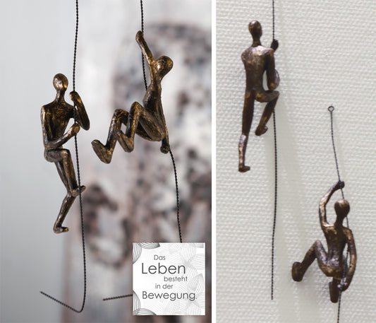 Das Ensemble "Scramble" besteht aus zwei Figuren aus Kunstharz in Bronze-Optik. Beide hängen kletternd an einem Seil herab.